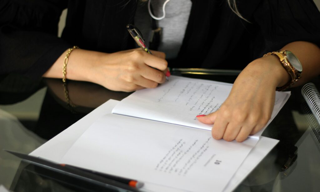 Close-up of person writing notes in a workbook
